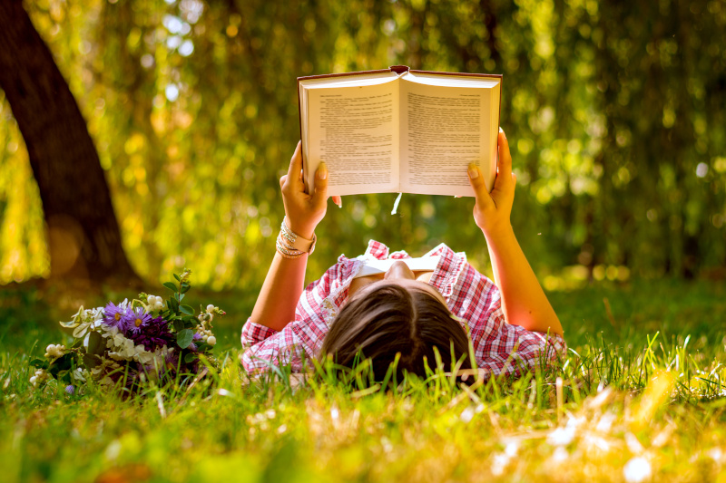 Junge Frau liest Buch im Gras
